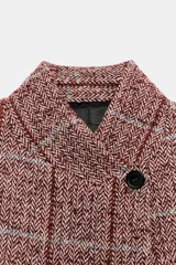 Blazer de lana con diseño de cuadros, cuello subido, manga larga, bolsillos delanteros y cierre frontal cruzado con un botón.