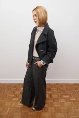 Chaqueta de paño color gris oscuro, con solapas amplias y cierre frontal mediante un alamar único. Presenta bolsillos laterales y mangas largas con puños rectos.