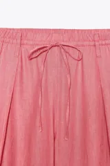 Pantalón de tiro alto color rosado, confeccionado en hilatura con lino, de pierna ancha y cintura elástica ajustable con cordones.