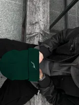 Gorro de lana verde oscuro con dobladillo y bordado blanco con la palabra "Just".