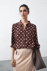Camisa de manga larga color marrón con estampado de lunares blancos, confeccionada en tejido liviano con cuello clásico y botones frontales.