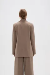 Blazer de corte holgado con diseño de rayas verticales, cuello solapa y cierre frontal con un botón. Presenta bolsillos laterales con solapa y mangas largas.