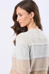 Buzo tejido de abrigo con cuello redondo y diseño a rayas horizontales en tonos gris, rosado, bordó y tostado. Cuenta con un pequeño aplique de cuero sintético con grabado en el borde inferior.