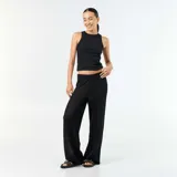 Pantalón de playa color negro, confeccionado en tejido de croché con patrón calado, de tiro medio y corte ancho en las piernas.