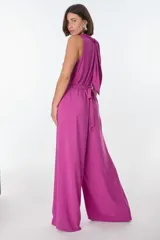 Mono largo fucsia de corte palazzo, sin mangas, con cuello halter que se ata en la nuca y cinturón de lazo.