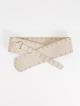 Faja ancha de cuero color beige, decorada con tachas metálicas en los bordes y hebilla circular metálica.