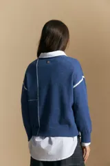 Sweater de punto color marrón con diseño de líneas blancas en contraste. Presenta cuello redondo, mangas largas y puños tejidos, con una estética minimalista y moderna.
