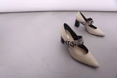 Zapato tipo stiletto con tira sobre el empeine, confeccionado en cuero color arena con detalle de tira en estampado de reptil y hebilla dorada. Cuenta con tacón bloque de altura media en color negro brillante.