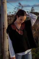 Chaleco tejido negro con cuello en V y aplique de cuero marrón.