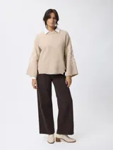 Jean de corte wide leg en color marrón, con tiro medio, cierre de botón y cremallera, y diseño clásico de cinco bolsillos.