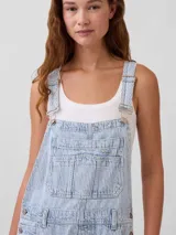 Mono enterito de denim celeste con diseño de rayas verticales blancas, corte holgado tipo horseshoe, tirantes ajustables y bolsillos frontales.