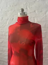 Minivestido rojo de microtul elastizado con estampado abstracto en tonos oscuros. Diseño ajustado con cuello alto y mangas largas.