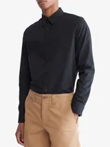 Camisa negra de manga larga con cuello clásico y cierre con botones. Tiene un pequeño logo de Calvin Klein bordado en el pecho.