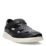 Sandalias tipo cerradas de cuero negro con diseño calado en la parte superior, cierre de velcro ajustable y suela de goma blanca.