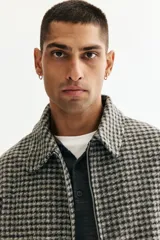 Sobrecamisa de fieltro con estampado de cuadros en tonos grises, cuello clásico, cierre bidireccional y bolsillos insertados en la parte delantera. Presenta un corte regular fit y no tiene forro.