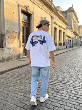 Remera blanca de algodón con cuello redondo y estampado en la espalda con la frase "Vinnare of Butterflies" y dos mariposas azules.