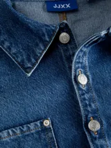 Sobrecamisa cropped de denim azul medio, con cuello clásico, mangas largas globo y dos bolsillos de parche con tapa en el pecho.