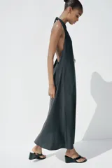 Vestido midi negro de tejido fluido, con cuello halter que se anuda en la nuca y escote pronunciado en pico.