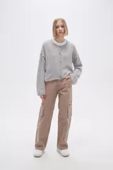 Cardigan de tejido de punto gris, con cuello redondo, cierre frontal con botones y mangas largas de corte holgado.