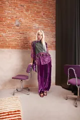 Musculosa de cuero color verde inglés, con diseño sin mangas y detalle de galón con borlas decorativas en color morado en los hombros y el ruedo.