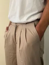 Pantalón sastrero de corte recto y holgado, color gris claro, con pinzas frontales y cintura con elástico posterior.