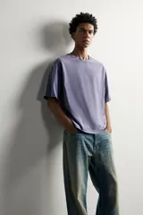 Camiseta relaxed fit de color gris con efecto lavado, cuello redondo y manga corta. Cuenta con un pequeño texto estampado en contraste en el pecho.