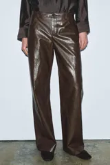 Pantalón de tiro medio, pierna recta, confeccionado en tejido efecto piel marrón oscuro con acabado arrugado. Presenta cinco bolsillos y cierre frontal con cremallera y botón.
