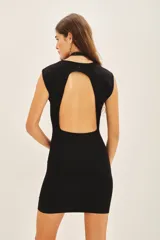 Vestido corto de punto color negro, con diseño sin mangas, cuello redondo y espalda descubierta.