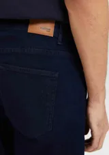 Pantalón de jean azul oscuro, de corte recto, con bolsillos laterales y traseros. Se ajusta a la cintura con botón y cierre. Fabricado en denim con elastano.