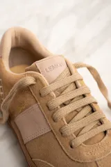 Zapatillas bajas color beige con detalles en cuero color crema.