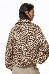Campera oversized de sarga con estampado de leopardo, cuello camisero, cierre frontal, bolsillos laterales ribeteados y puños elásticos.