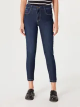 Pantalón de jean ajustado (skinny) de tiro medio, color azul oscuro (índigo) con costuras en hilo contrastante color mostaza. El largo es tobillero.