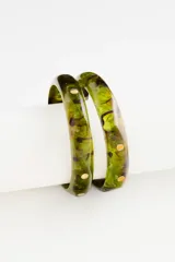 Set de dos pulseras tipo brazalete rígido de resina en tono verde con efecto jaspeado y detalles de pequeños puntos metálicos dorados incrustados.
