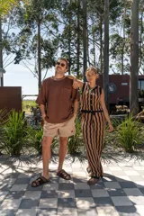 Pantalón tejido de corte recto y tiro alto, con diseño de rayas verticales onduladas en colores beige y negro. Presenta una cintura elástica con cordón ajustable.