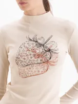 Top de manga larga en color crema, confeccionado en tejido acanalado con cuello alto y estampado frontal de una fresa.