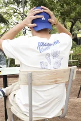 Remera blanca de algodón con estampado en la espalda con la frase "Follow the Waves" y dibujos de conchas marinas en color celeste.