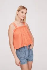 Musculosa color salmón con breteles finos y detalle de puntilla en el escote.