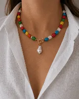 Collar de cuentas irregulares multicolor con cierre frontal tipo toggle dorado y dije central de perla barroca.