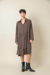 Túnica marrón con estampado geométrico negro en la parte inferior, cuello camisero y abotonadura frontal.