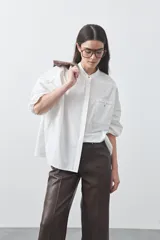 Camisa de manga larga en color celeste, con cuello mao y cierre frontal oculto. Presenta un diseño de silueta relajada con sisa caída y un bolsillo aplicado en el pecho.