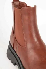 Botas Chelsea negras de cuero sintético con elástico en los laterales, detalle de textura símil cocodrilo en el talón y suela track.