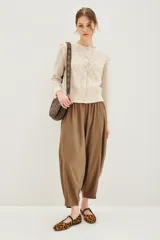 Pantalón tipo babucha de corte holgado y tiro alto, con cintura elástica y diseño de pierna amplia que se estrecha hacia los tobillos.