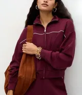 Campera de cuello alto en color bordó, con cierre frontal metálico y detalle de piping en contraste. Presenta puños y ruedo acanalados, con un diseño de corte deportivo y moderno.