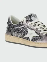 Zapatillas Golden Goose modelo Ballstar, con cuerpo cubierto de glitter negro y plateado, puntera laminada en tono oscuro, estrella lateral blanca y suela de aspecto desgastado.