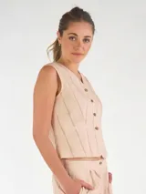 Chaleco sastrero de lino color beige con diseño de rayas verticales, escote en V y cierre frontal con botones.