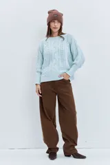 Sweater de punto en color celeste, con diseño de trenzas y textura en relieve. Presenta cuello redondo, mangas largas con puños ajustados y un corte holgado.