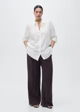 Camisa de lyocell color blanco, con cuello camisero, manga larga con puños abotonados, diseño recto y cierre frontal con botones ocultos.