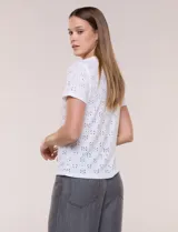 Remera blanca de calce recto con diseño de bordado calado estilo broderie, cuello redondo clásico y mangas cortas.
