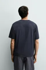 Set de pijama compuesto por una remera lisa de manga corta con cuello redondo y una bermuda a cuadros con bolsillos laterales y cintura elástica.