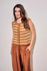 Chaleco de punto sin mangas con diseño de rayas horizontales en tonos marrones, amarillos y beige. Presenta un cierre frontal con botones y cuello redondo con terminación acanalada.